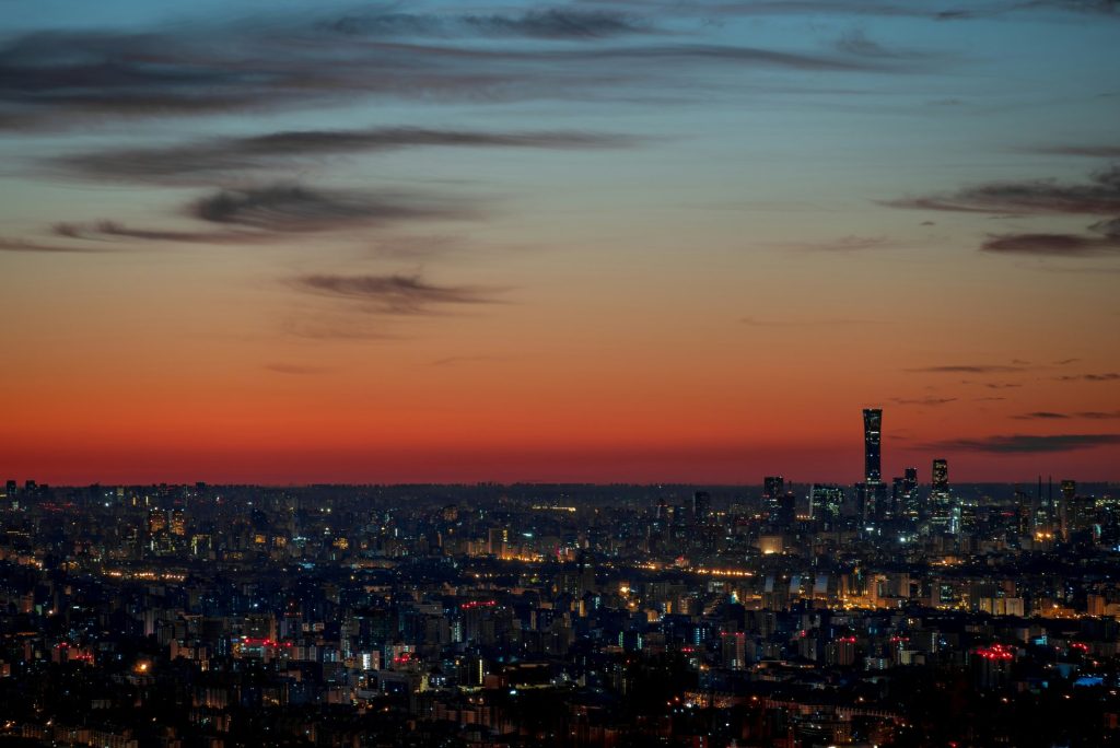 Blick auf eine Stadt bei Nacht von der Spitze eines Hügels